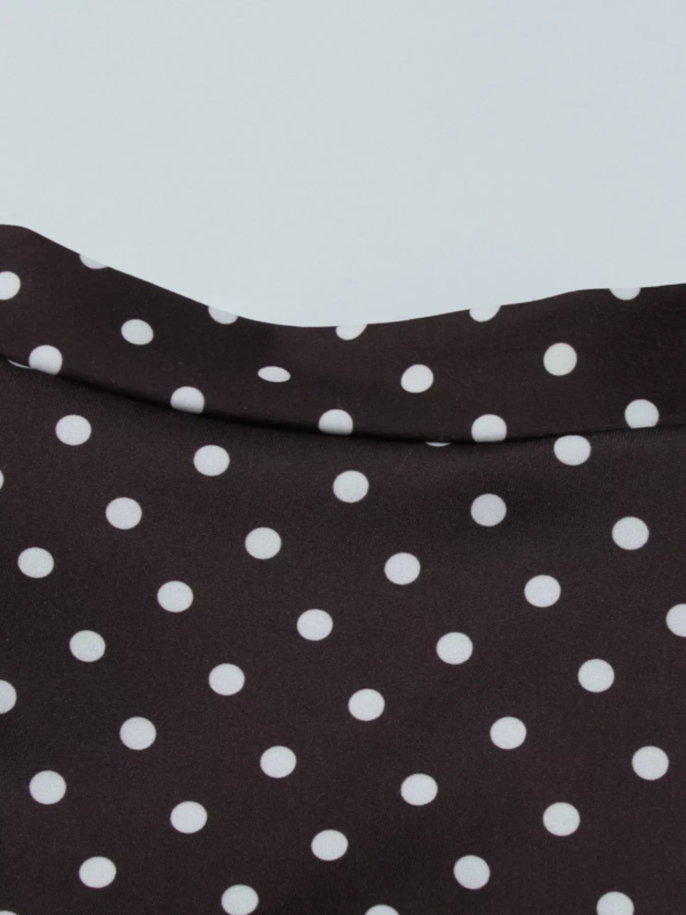Black fabric with white polka dots on a light gray background