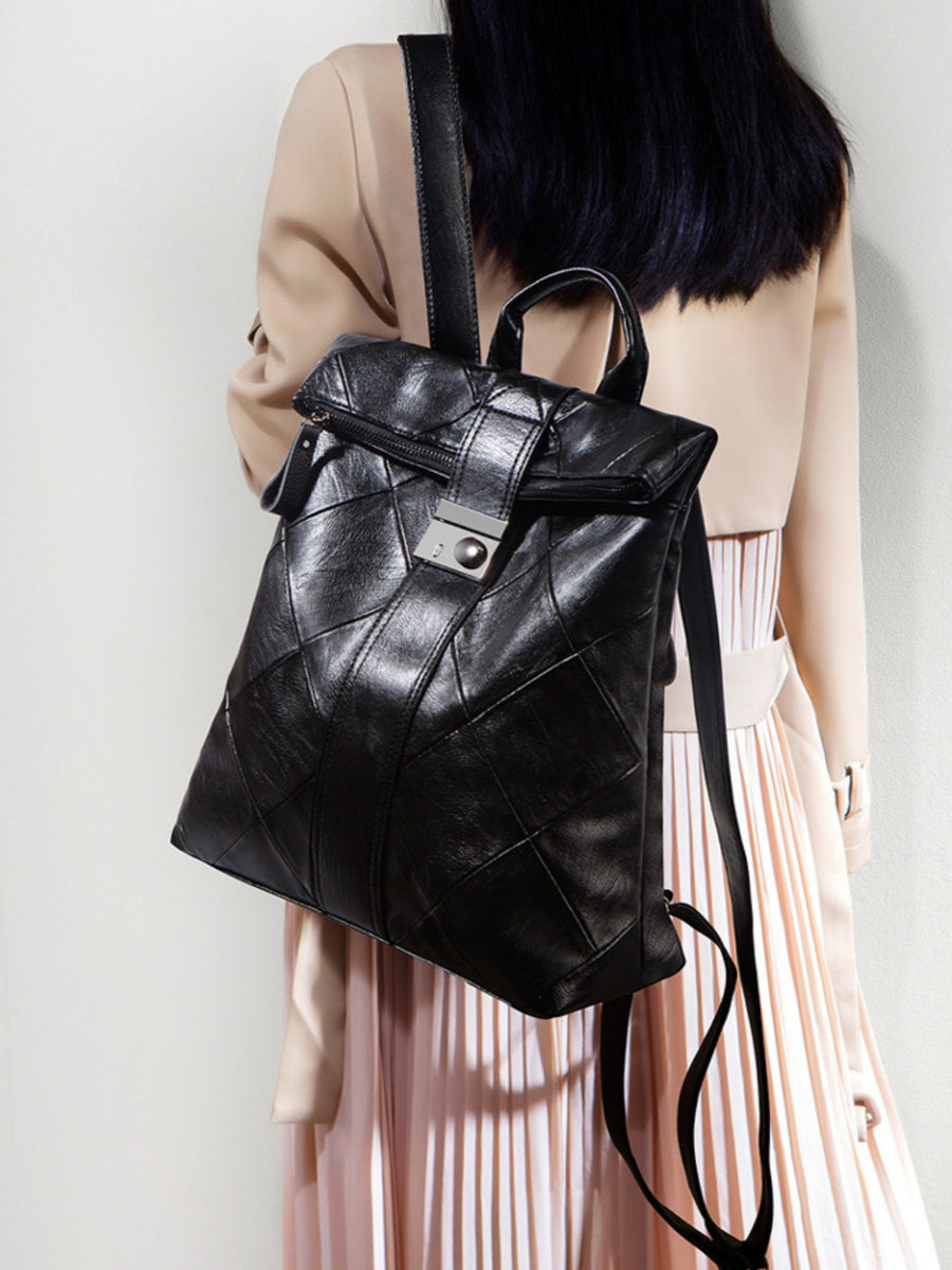 Black leather backpack worn by a person on a plain background