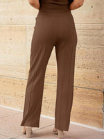 Brown pants worn by a person against a stone wall background