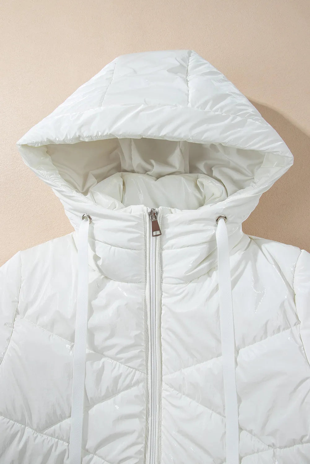 White quilted jacket with a hood on a beige background