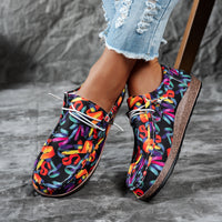 Colorful patterned shoes worn with denim jeans on a gray surface