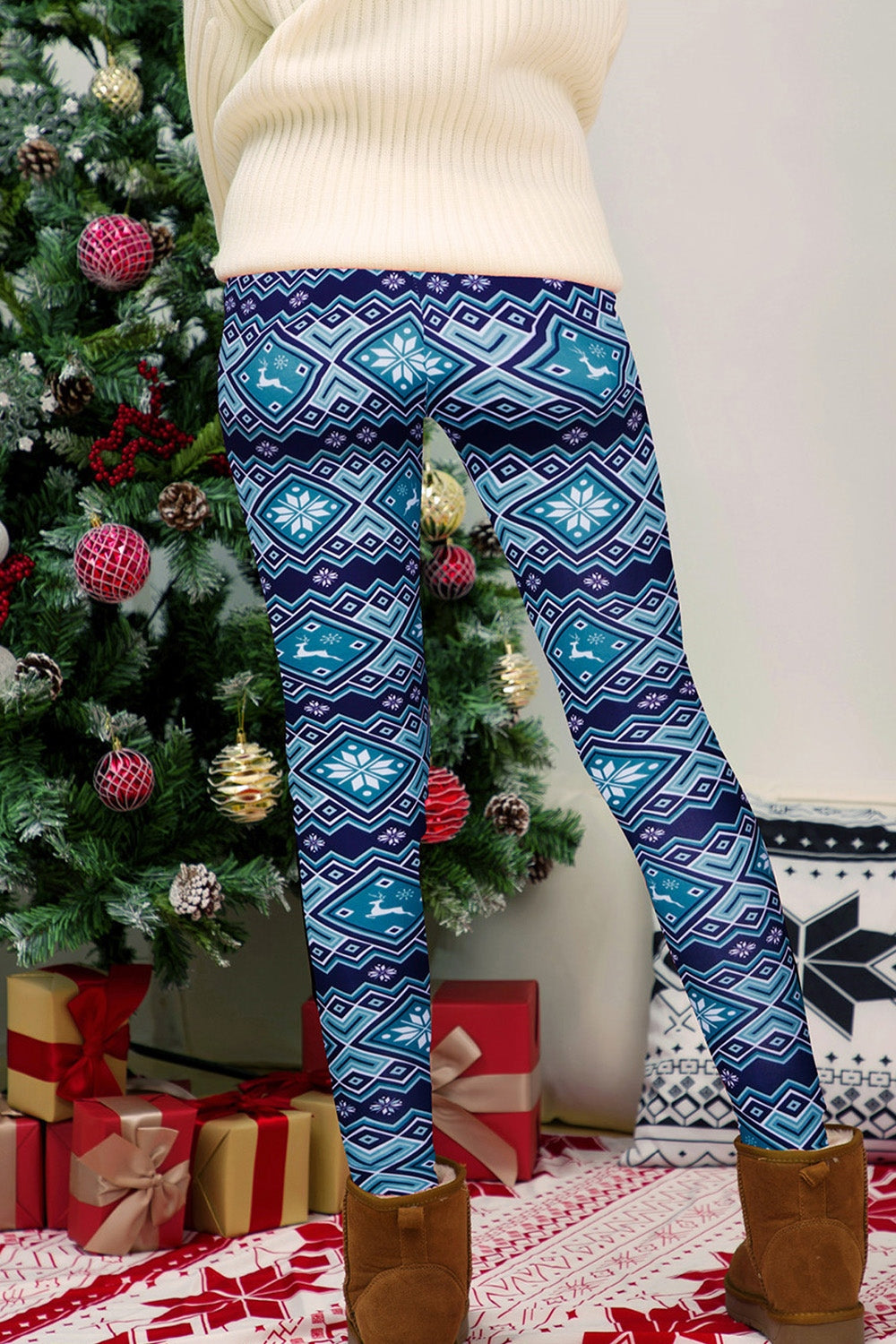 Person wearing blue patterned leggings standing in front of a decorated Christmas tree.