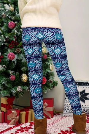Person wearing blue patterned leggings standing in front of a decorated Christmas tree.