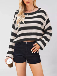 Person wearing a black and white striped sweater and black shorts on a plain background