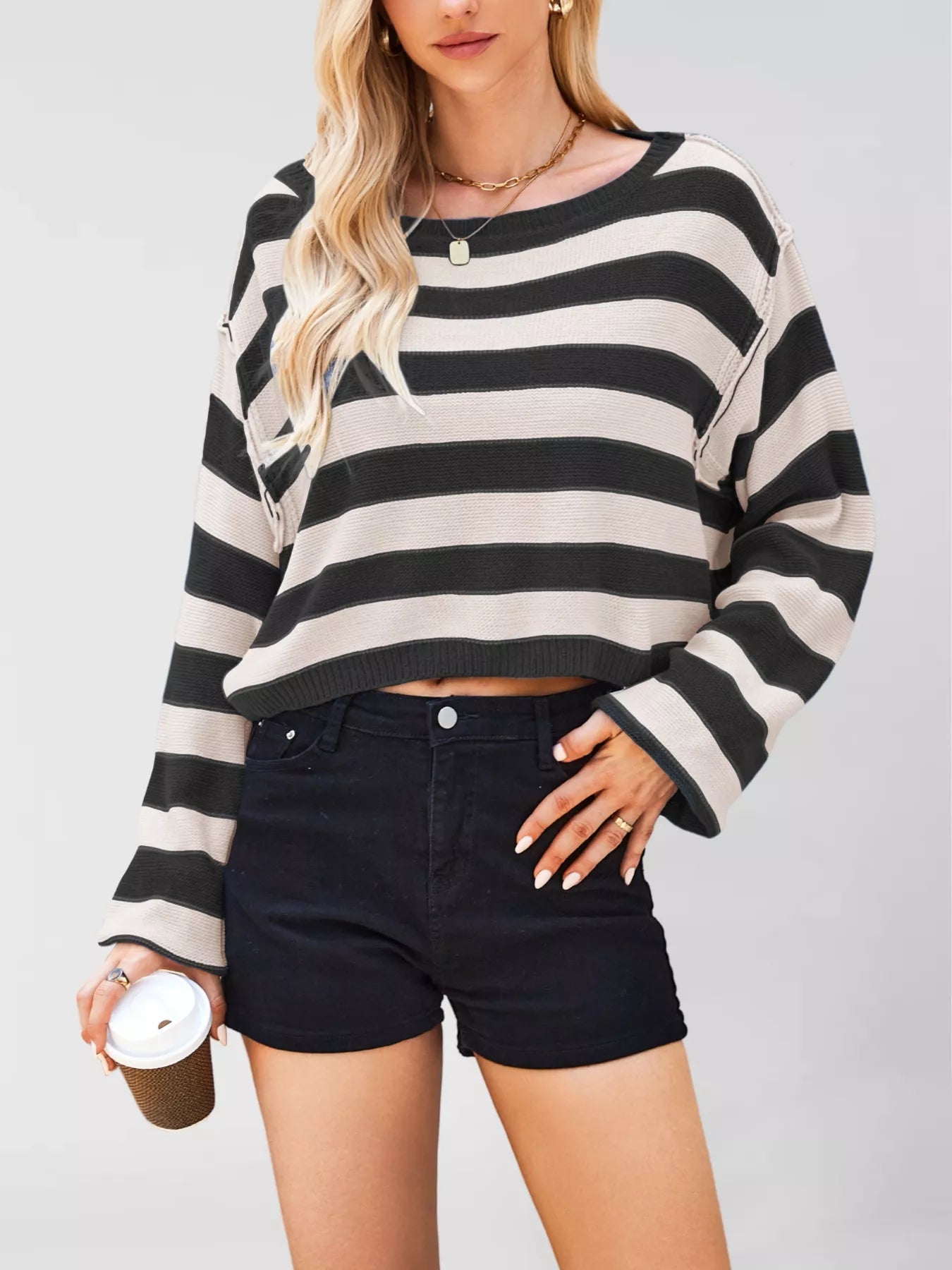 Person wearing a black and white striped sweater and black shorts on a plain background