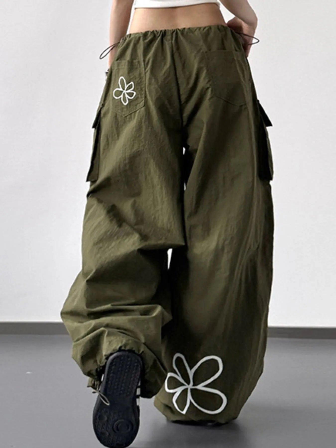 Green baggy pants with white flower designs on a plain background