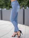 Person wearing blue jeans and black high-heeled shoes on a sidewalk.