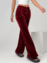 Red velvet pants worn by a person on a white background