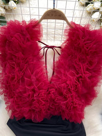 Red ruffled top on a hanger with a white floral background
