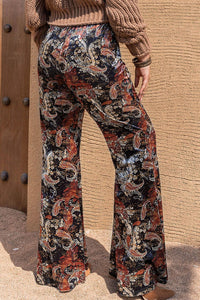 Person wearing patterned pants standing against a textured wall.