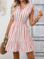 Woman wearing a pink and white striped dress against a wooden wall.