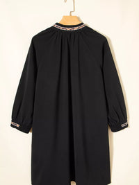 Black dress with lace trim on a hanger against a white background