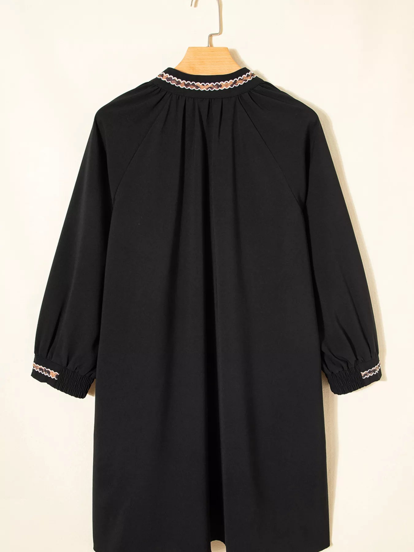 Black dress with lace trim on a hanger against a white background