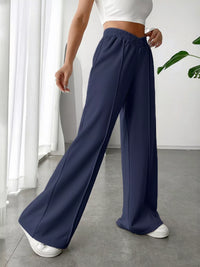 Person wearing navy wide-leg pants in a minimal indoor setting