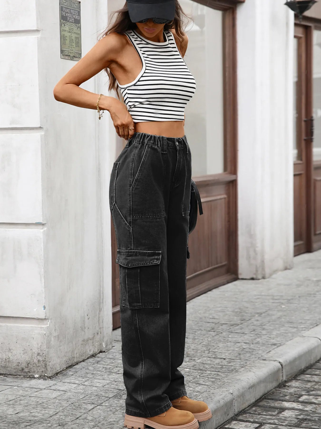 Person wearing a black and white striped crop top and black cargo pants standing on a street.
