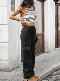 Person wearing a black and white striped crop top and black cargo pants standing on a street.