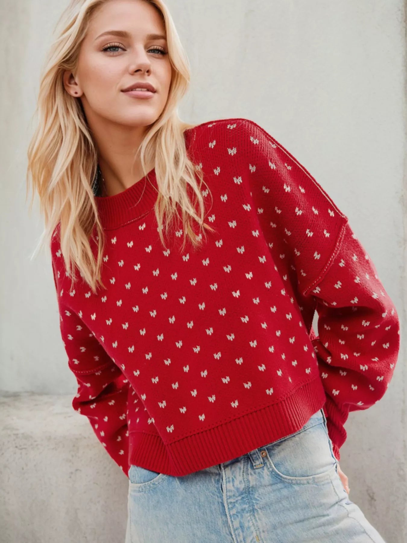 Woman wearing a red sweater with a pattern against a neutral background