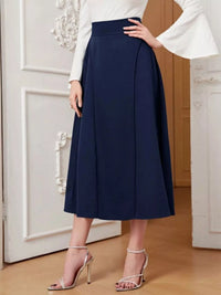 Person wearing a navy blue skirt with a white top in an indoor setting.
