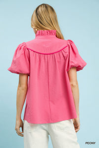 Pink blouse with puff sleeves worn by a person on a light blue background