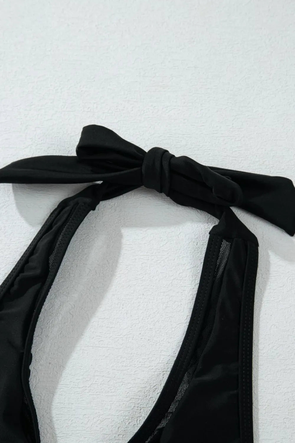 Black bikini top with a bow on a white background