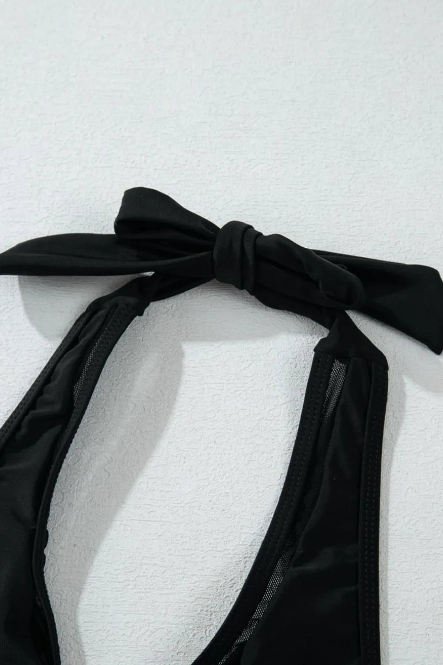Black bikini top with a bow on a white background