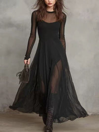 Woman wearing a long black dress with sheer sleeves against a gray background