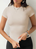 Woman wearing a beige ribbed top and black pants against a plain background