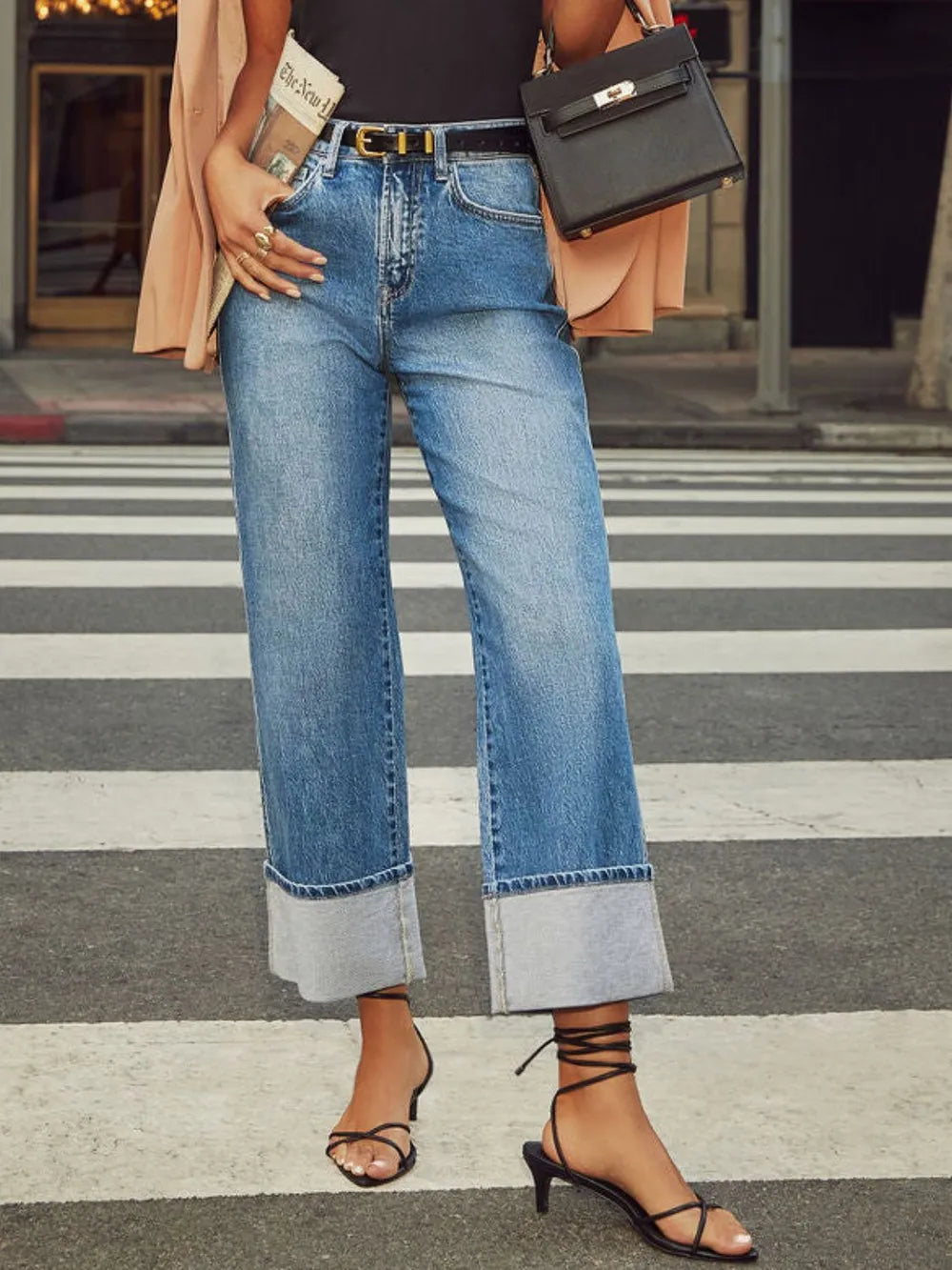 Person wearing blue jeans and black sandals on a crosswalk