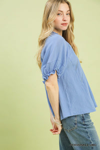 Woman wearing a light blue blouse with puff sleeves on a light green background