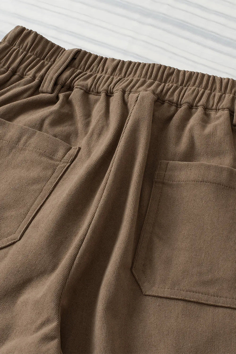 Close-up of brown pants with pockets on a light gray background