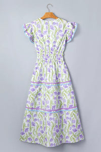 Green and purple floral dress on a hanger against a gray background