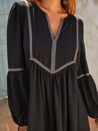 Black dress with intricate detailing on a neutral background