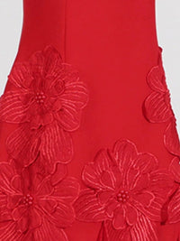 Red fabric with floral embroidery on a white background