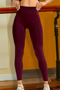 Person wearing maroon leggings standing against a neutral background
