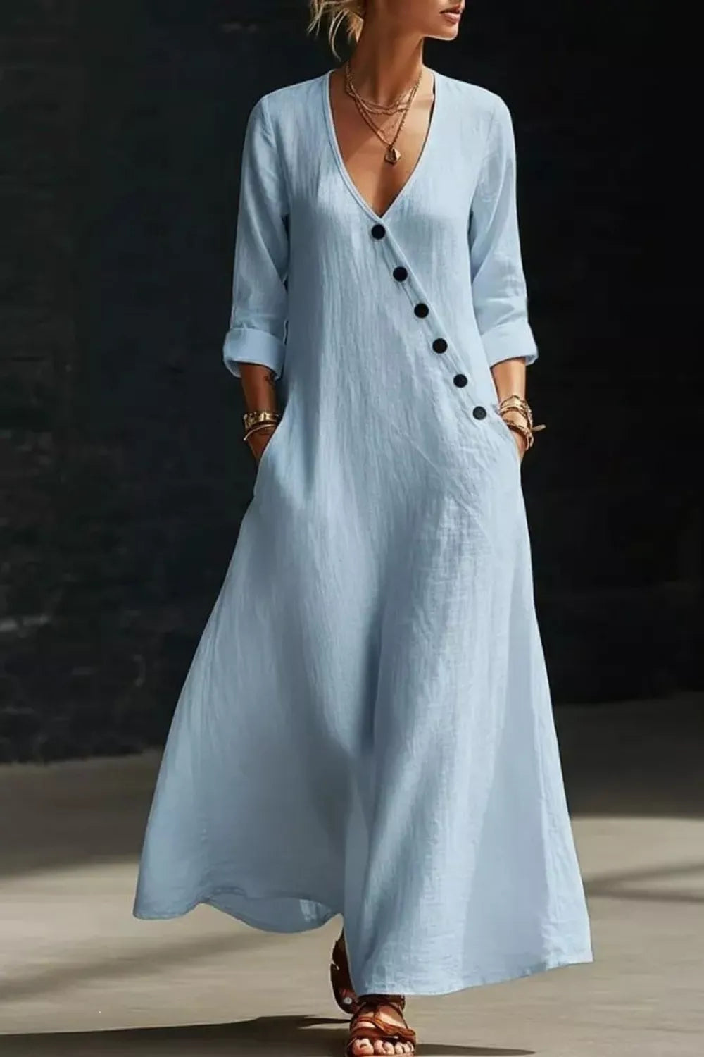 Woman wearing a light blue dress with black buttons against a dark background