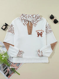 White sweater with leopard print accents on a beige background