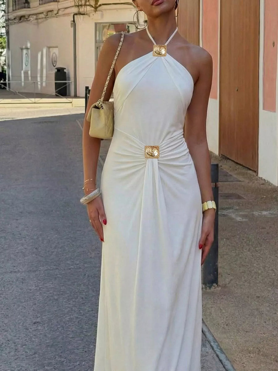Woman in a white one-shoulder dress with gold accents standing on a street.