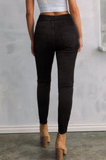 Person wearing black pants and tan boots against a plain background