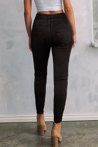 Person wearing black pants and tan boots against a plain background