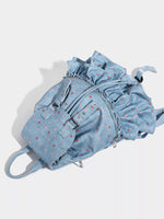 Light blue denim backpack with ruffled details on a white background