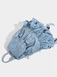Light blue denim backpack with ruffled details on a white background