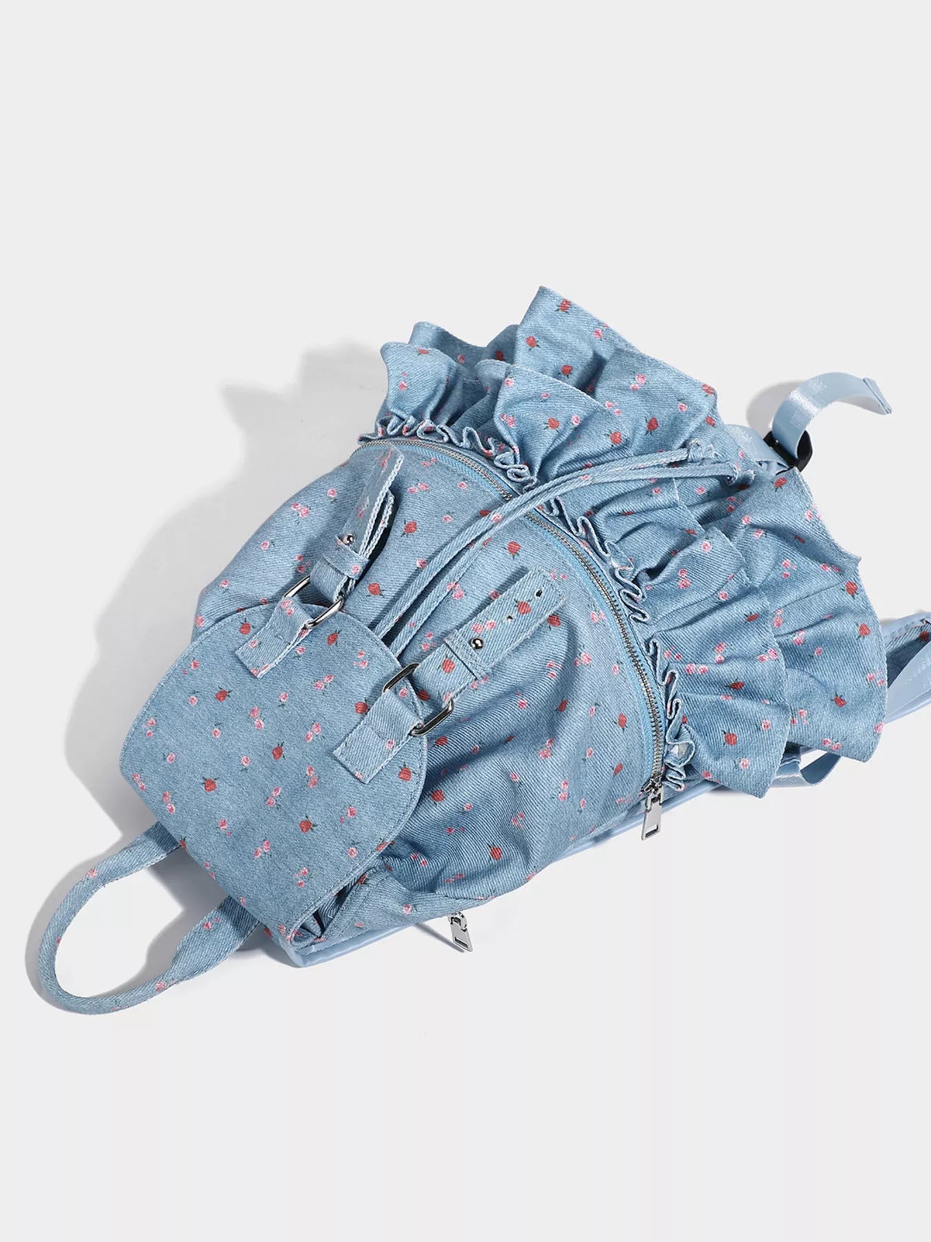Light blue denim backpack with ruffled details on a white background