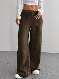 Person wearing brown wide-leg pants with a plain background