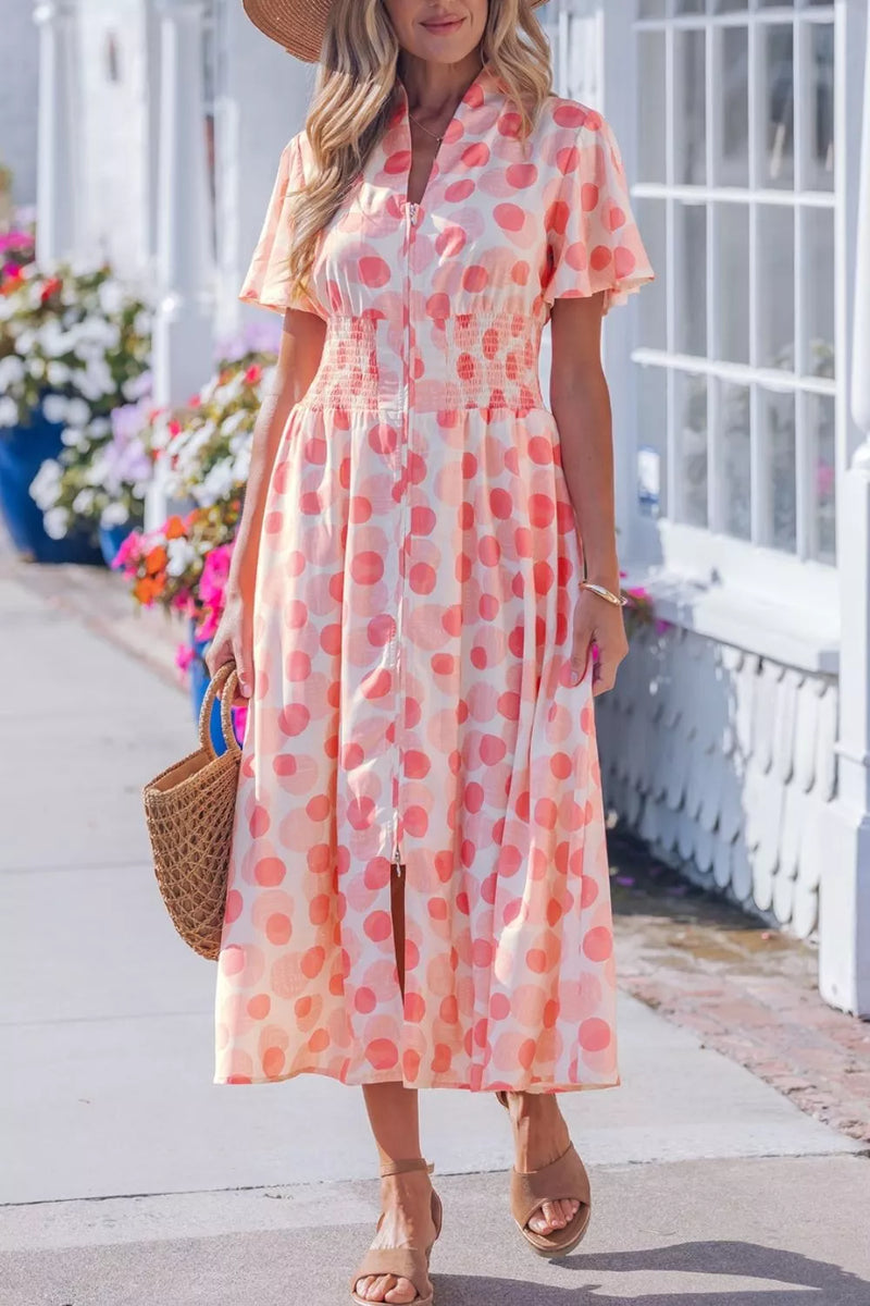 Woman wearing a polka dot dress with a straw bag on a sunlit path.