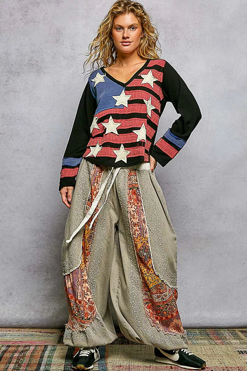 Woman wearing a colorful sweater and patterned pants against a gray background