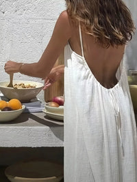 Person in a white dress standing next to a table with food items.