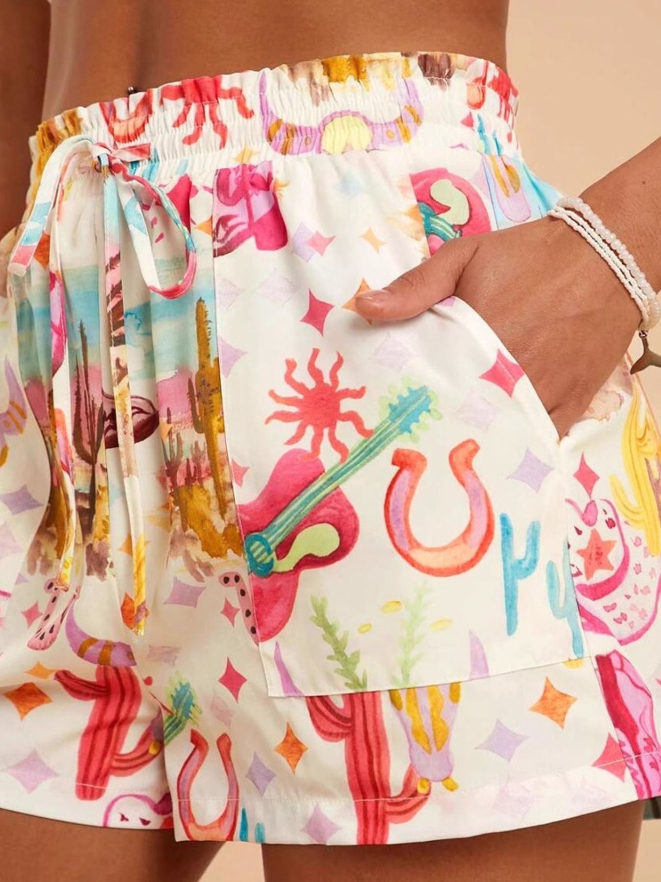 Colorful shorts with a pattern of horses, stars, and cacti on a white background.