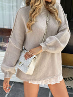 Woman wearing a beige sweater dress with a white handbag indoors.