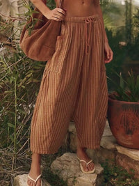 Person wearing brown striped pants and holding a brown bag in an outdoor setting.