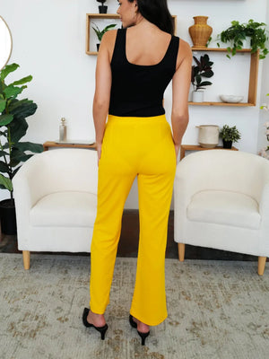 Person wearing a black top and yellow pants in a living room setting